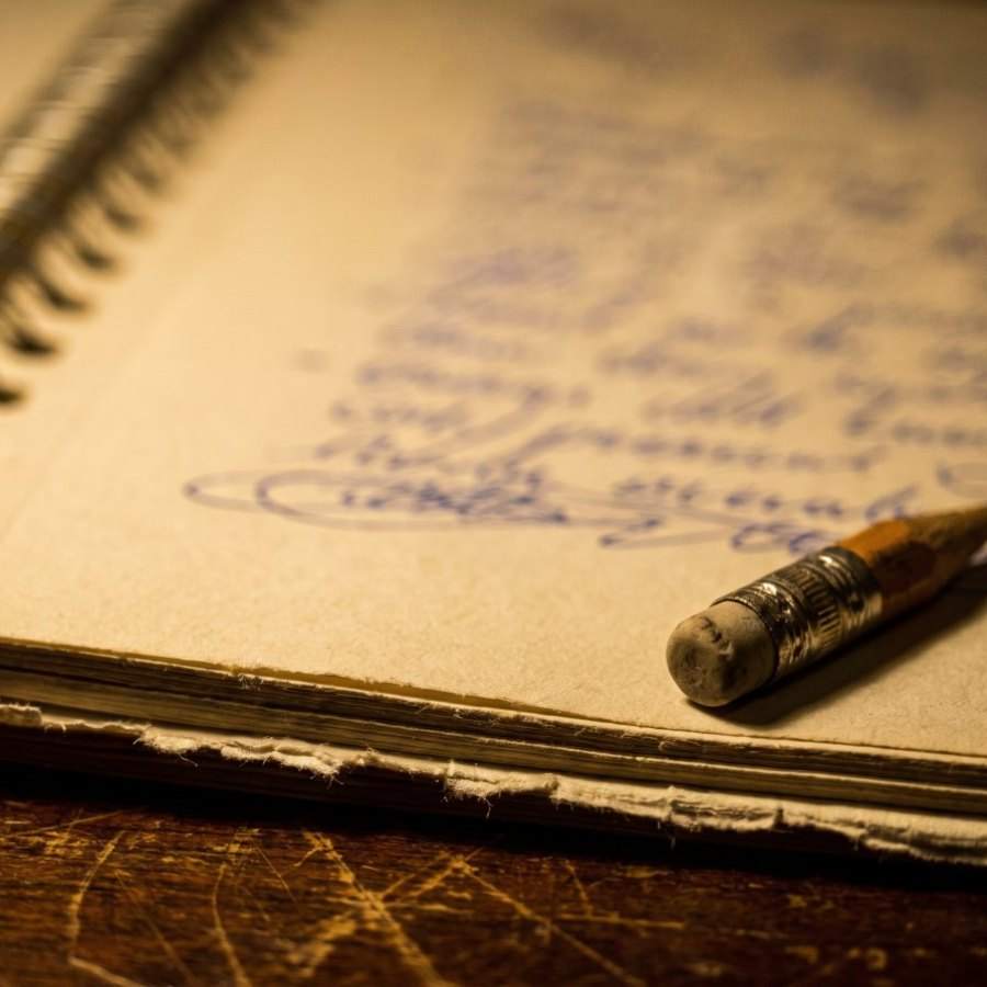 Handwritten lyric notes in a worn spiral notebook